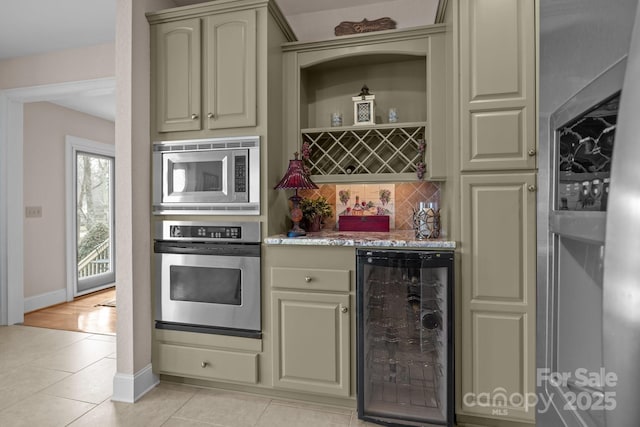 kitchen with tasteful backsplash, beverage cooler, light tile patterned floors, stainless steel appliances, and cream cabinetry