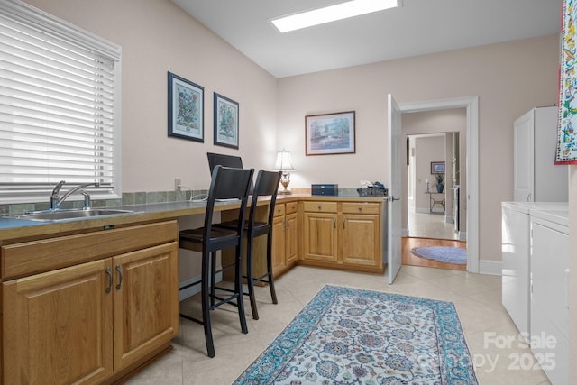 interior space with separate washer and dryer, sink, and light tile patterned floors