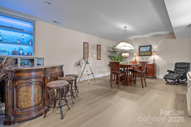 dining area featuring light hardwood / wood-style flooring and indoor bar