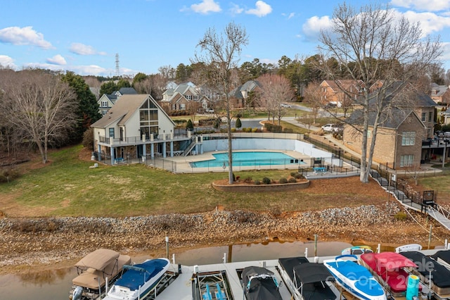 view of pool with a water view, a dock, and a lawn