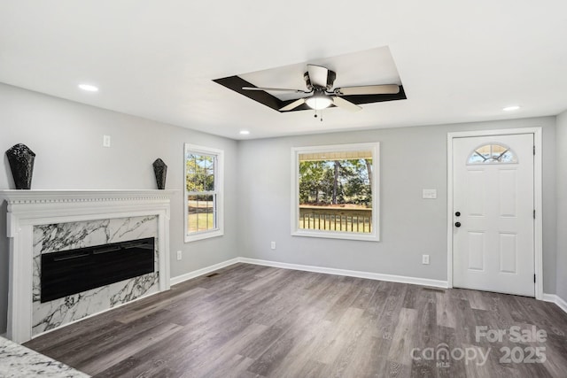 unfurnished living room featuring ceiling fan, wood-type flooring, and a fireplace