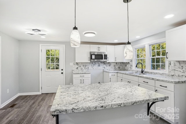 kitchen with hanging light fixtures, white cabinetry, sink, and a kitchen bar