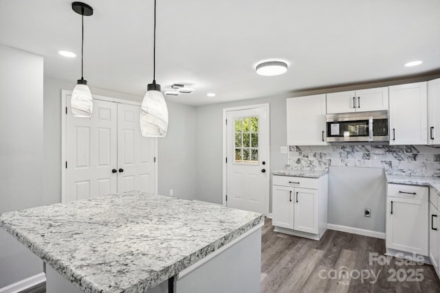 kitchen featuring a kitchen island, decorative light fixtures, white cabinets, backsplash, and dark wood-type flooring