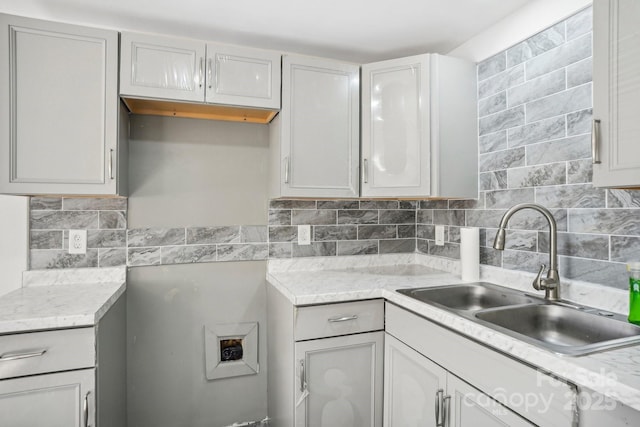 kitchen with light stone countertops, sink, and backsplash