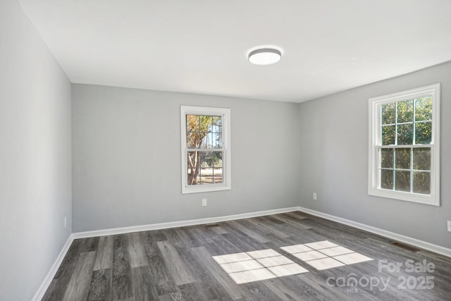 spare room with dark hardwood / wood-style floors and a healthy amount of sunlight