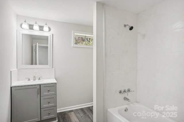 bathroom with vanity, hardwood / wood-style flooring, and tiled shower / bath