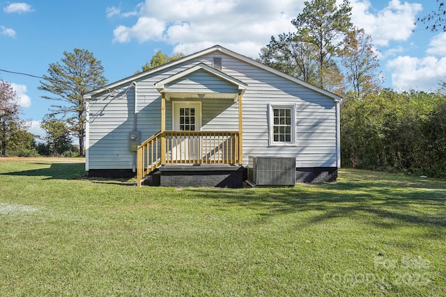 rear view of property featuring central AC and a lawn