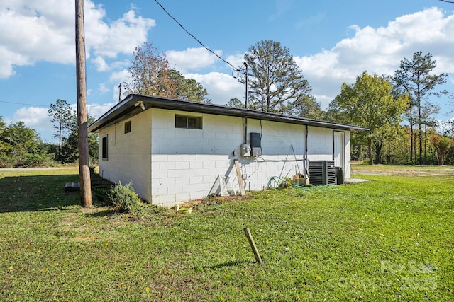 view of side of property with central AC unit and a lawn