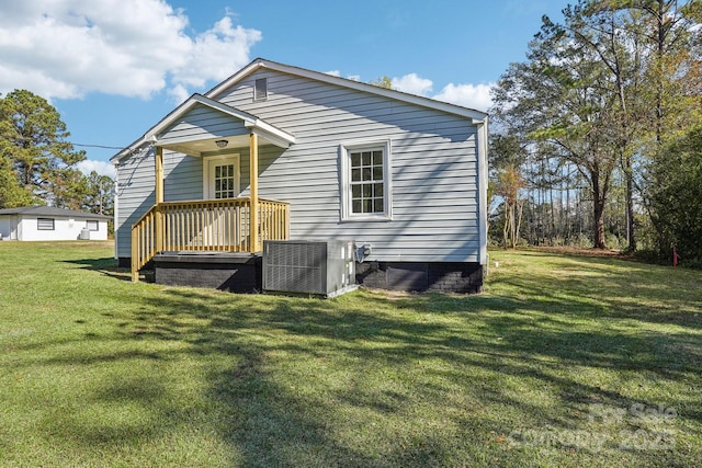 rear view of house featuring central AC unit and a lawn