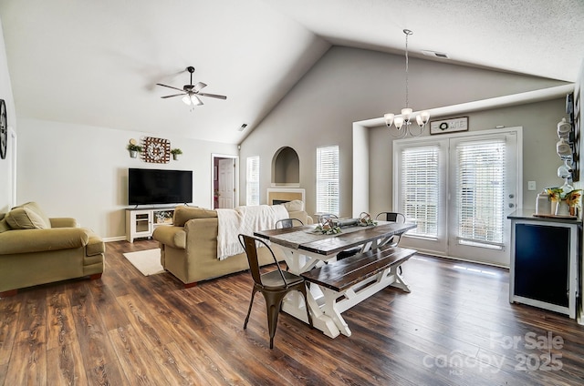 dining space featuring dark hardwood / wood-style floors, ceiling fan with notable chandelier, and high vaulted ceiling