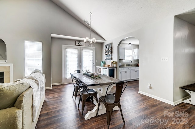 dining space featuring high vaulted ceiling, dark hardwood / wood-style floors, sink, and a notable chandelier