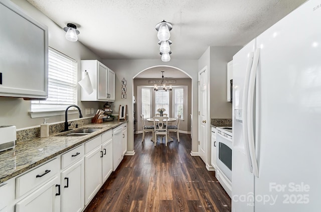 kitchen featuring dark hardwood / wood-style floors, stone countertops, sink, white cabinets, and white appliances