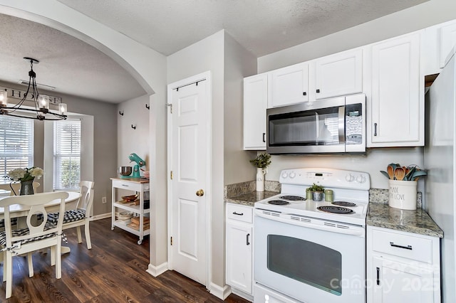 kitchen with white electric range oven, hanging light fixtures, dark stone countertops, dark hardwood / wood-style floors, and white cabinets