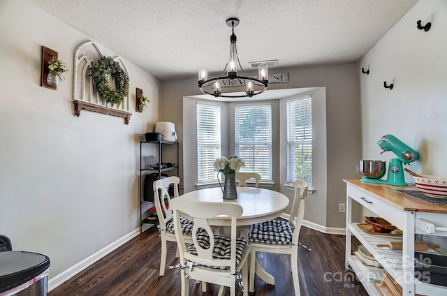 dining space featuring dark hardwood / wood-style floors, a textured ceiling, and a chandelier