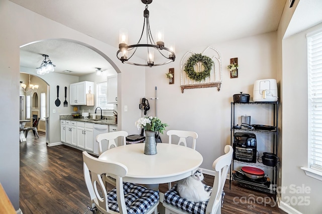 dining room featuring sink, dark wood-type flooring, and a chandelier