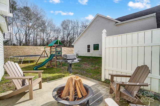 view of patio featuring a playground, a trampoline, and an outdoor fire pit