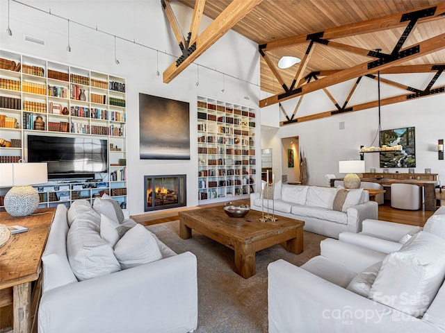 living room featuring beamed ceiling, high vaulted ceiling, built in features, and wood ceiling