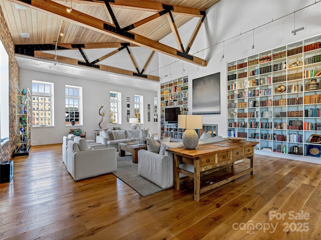 living room featuring wood-type flooring, high vaulted ceiling, and beamed ceiling