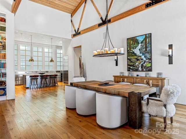 dining area featuring an inviting chandelier, high vaulted ceiling, and light hardwood / wood-style floors