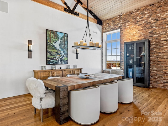 dining room with brick wall, hardwood / wood-style floors, wooden ceiling, and high vaulted ceiling