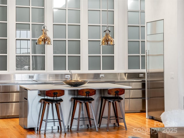 bar featuring light hardwood / wood-style flooring, stainless steel counters, and stainless steel built in fridge