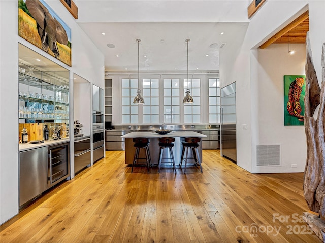 bar featuring pendant lighting, stainless steel built in refrigerator, light hardwood / wood-style floors, and wine cooler