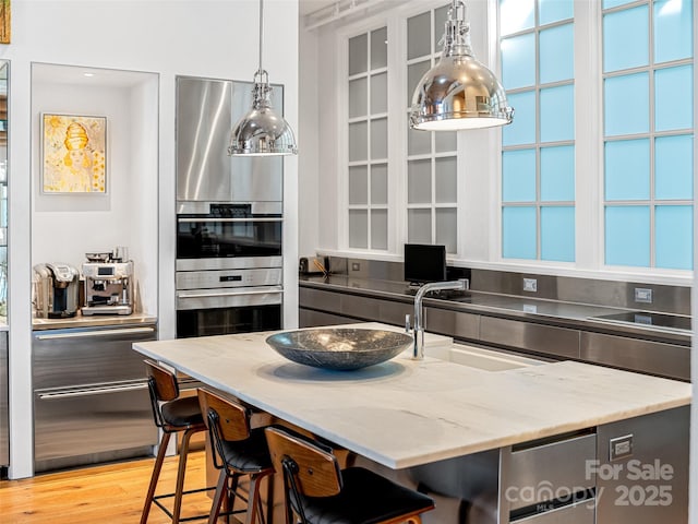 kitchen featuring sink, light stone counters, a kitchen breakfast bar, and light hardwood / wood-style floors