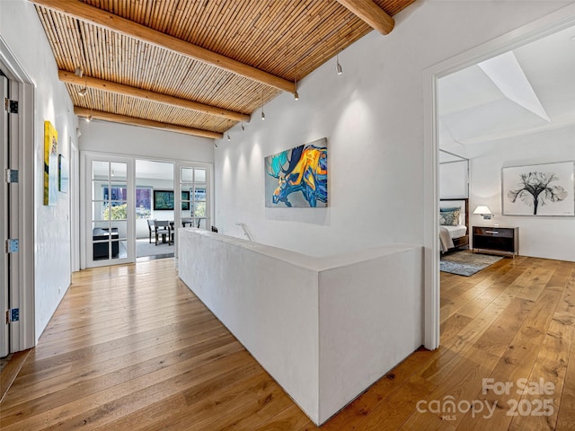 hall with beamed ceiling, light hardwood / wood-style floors, and wooden ceiling