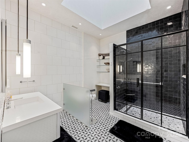 bathroom with tile walls, vanity, a shower with shower door, and tile patterned floors