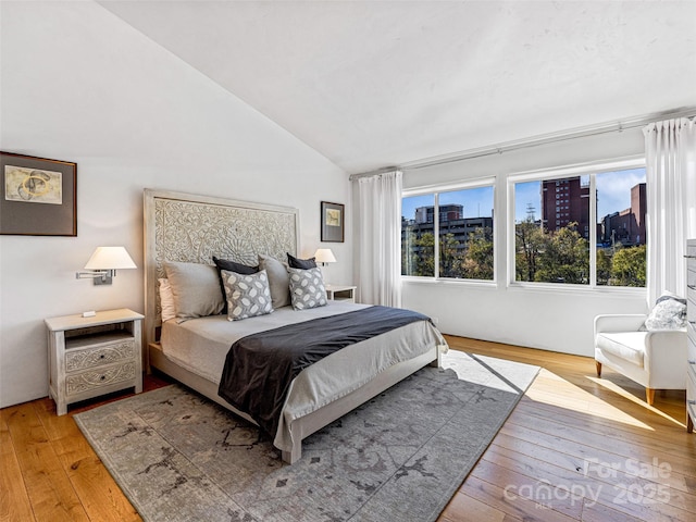 bedroom with lofted ceiling and light wood-type flooring