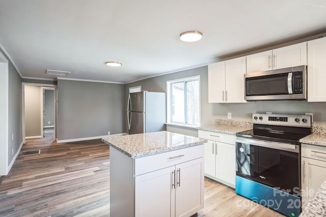 kitchen with white cabinetry, light stone counters, ornamental molding, and stainless steel appliances