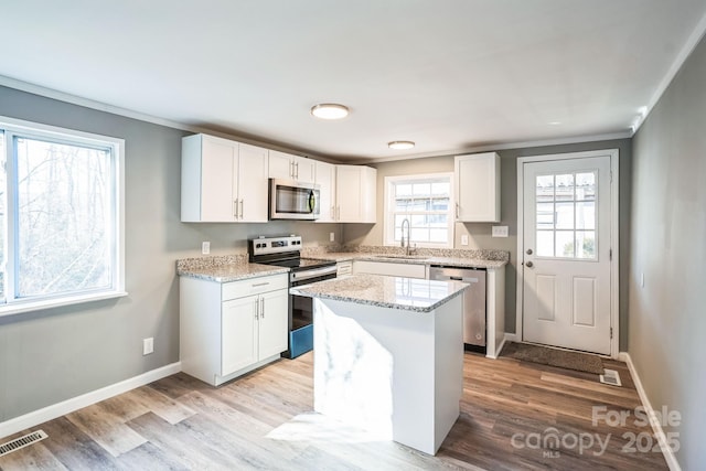 kitchen with white cabinetry, sink, a kitchen island, and appliances with stainless steel finishes