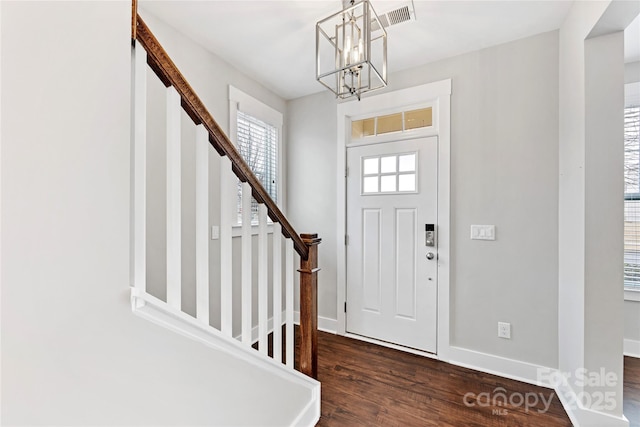 foyer entrance with dark hardwood / wood-style flooring and an inviting chandelier