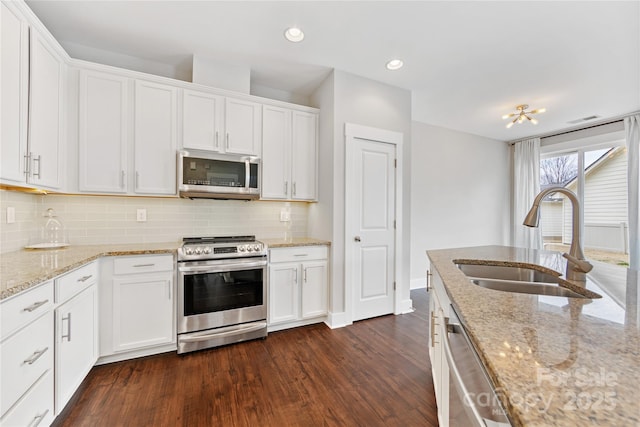 kitchen with sink, white cabinets, dark hardwood / wood-style flooring, light stone counters, and stainless steel appliances