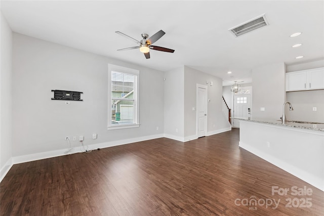 unfurnished living room with ceiling fan with notable chandelier, dark hardwood / wood-style floors, and sink