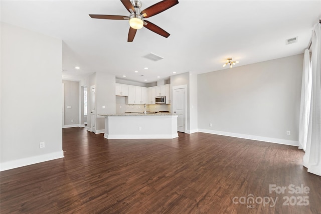 unfurnished living room featuring dark wood-type flooring, sink, and ceiling fan