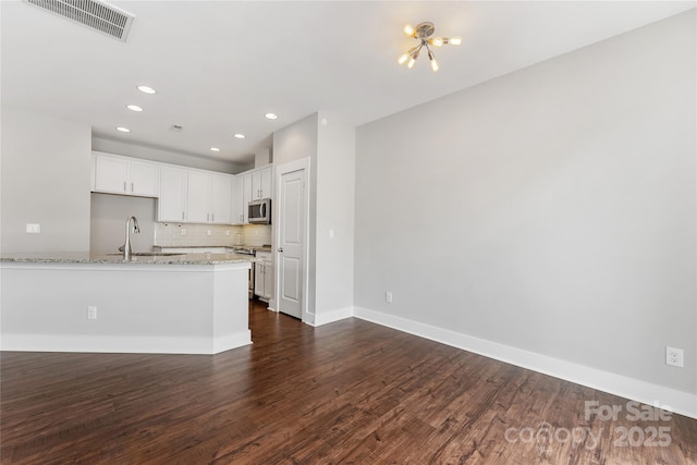 kitchen with sink, light stone counters, stainless steel appliances, decorative backsplash, and white cabinets