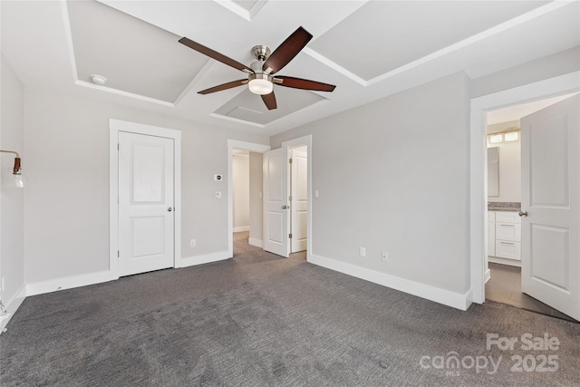 unfurnished bedroom featuring ceiling fan, ensuite bathroom, and dark carpet