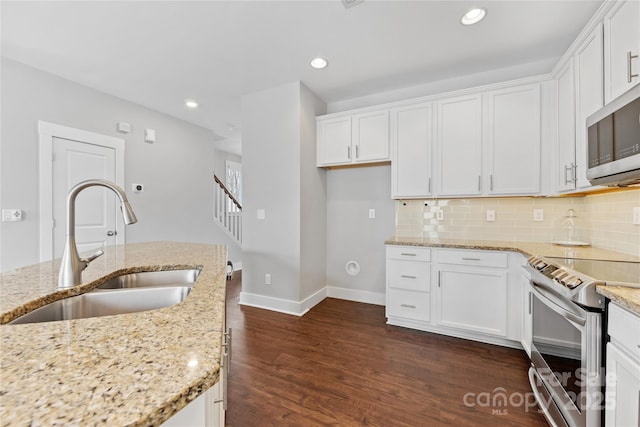 kitchen with sink, backsplash, white cabinets, light stone counters, and stainless steel appliances