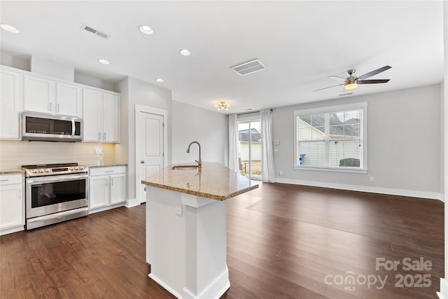 kitchen with white cabinetry, stainless steel appliances, sink, and a center island with sink