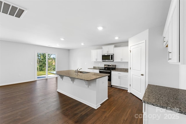 kitchen featuring sink, dark stone countertops, appliances with stainless steel finishes, an island with sink, and white cabinets