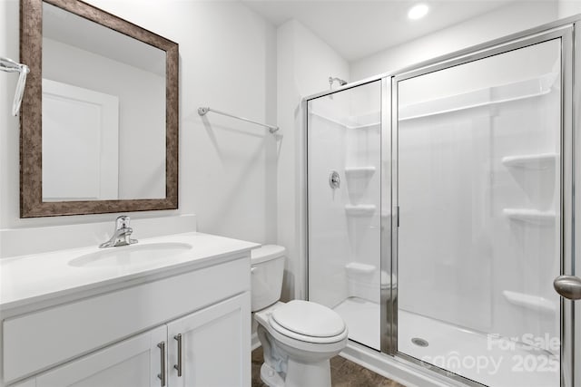 bathroom with a shower with door, vanity, and toilet