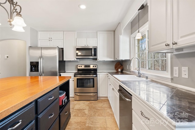 kitchen with pendant lighting, sink, white cabinetry, and stainless steel appliances