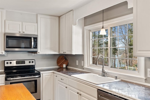 kitchen with stainless steel appliances, hanging light fixtures, sink, and white cabinets