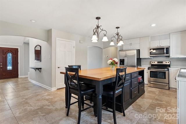 kitchen featuring a breakfast bar, pendant lighting, white cabinetry, a center island, and stainless steel appliances