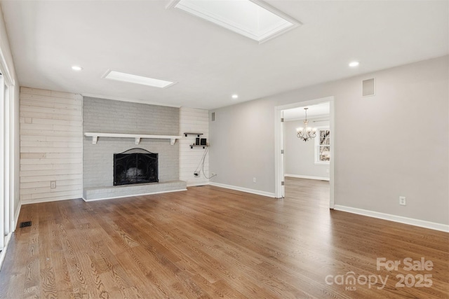 unfurnished living room with a skylight, hardwood / wood-style flooring, and a fireplace