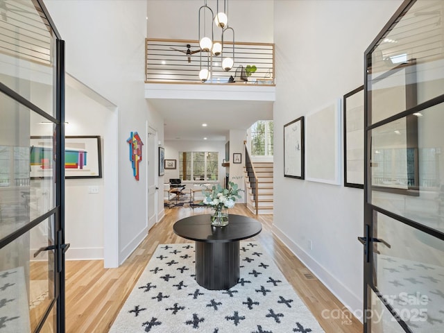 entrance foyer featuring an inviting chandelier, a high ceiling, and light wood-type flooring