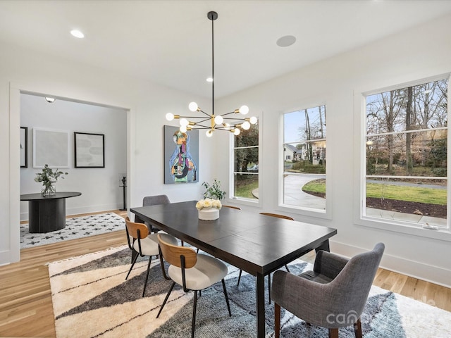 dining space with a healthy amount of sunlight, hardwood / wood-style floors, and a chandelier