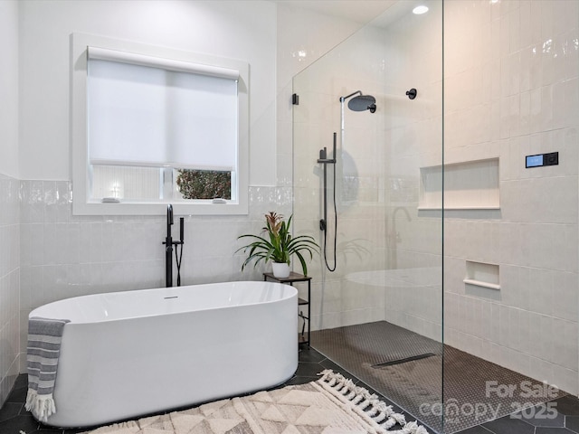 bathroom featuring tile patterned floors, plus walk in shower, and tile walls