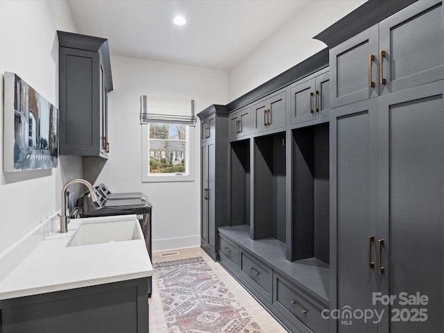 washroom with cabinets, washer and clothes dryer, and sink